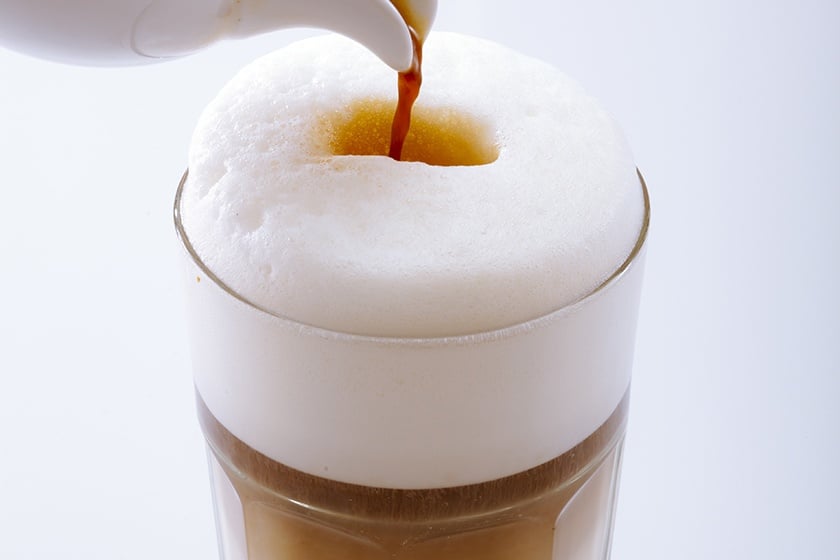 Espresso wird in ein Glas Milch gegossen