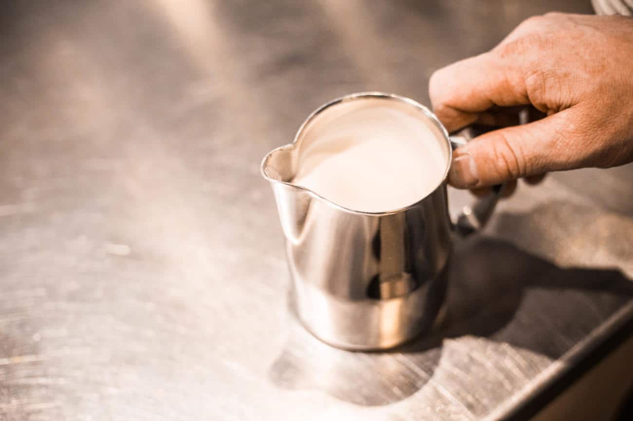barista schwenkt milchkanne